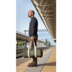 Homme tenant un sac de voyage sur un quai